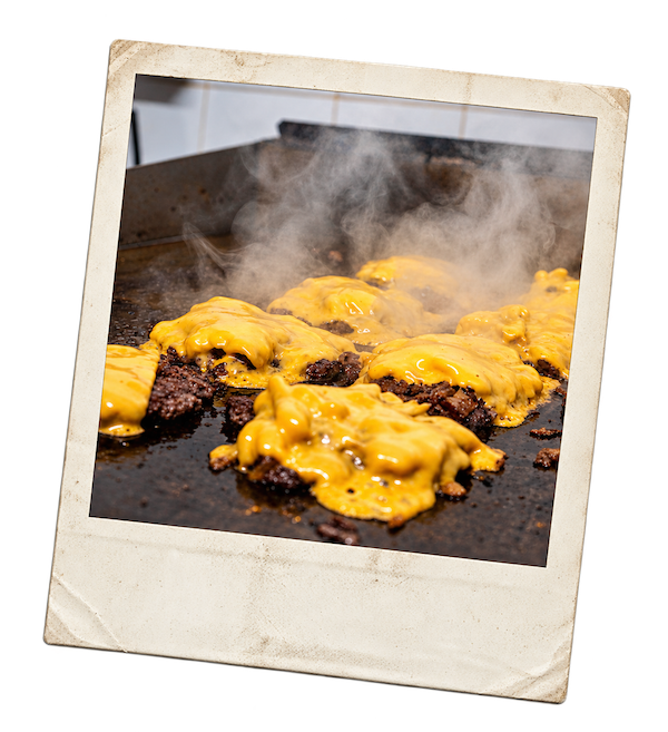 Patties capped with melting cheese steaming on the Crack Burger griddle, printed as a retro polaroid