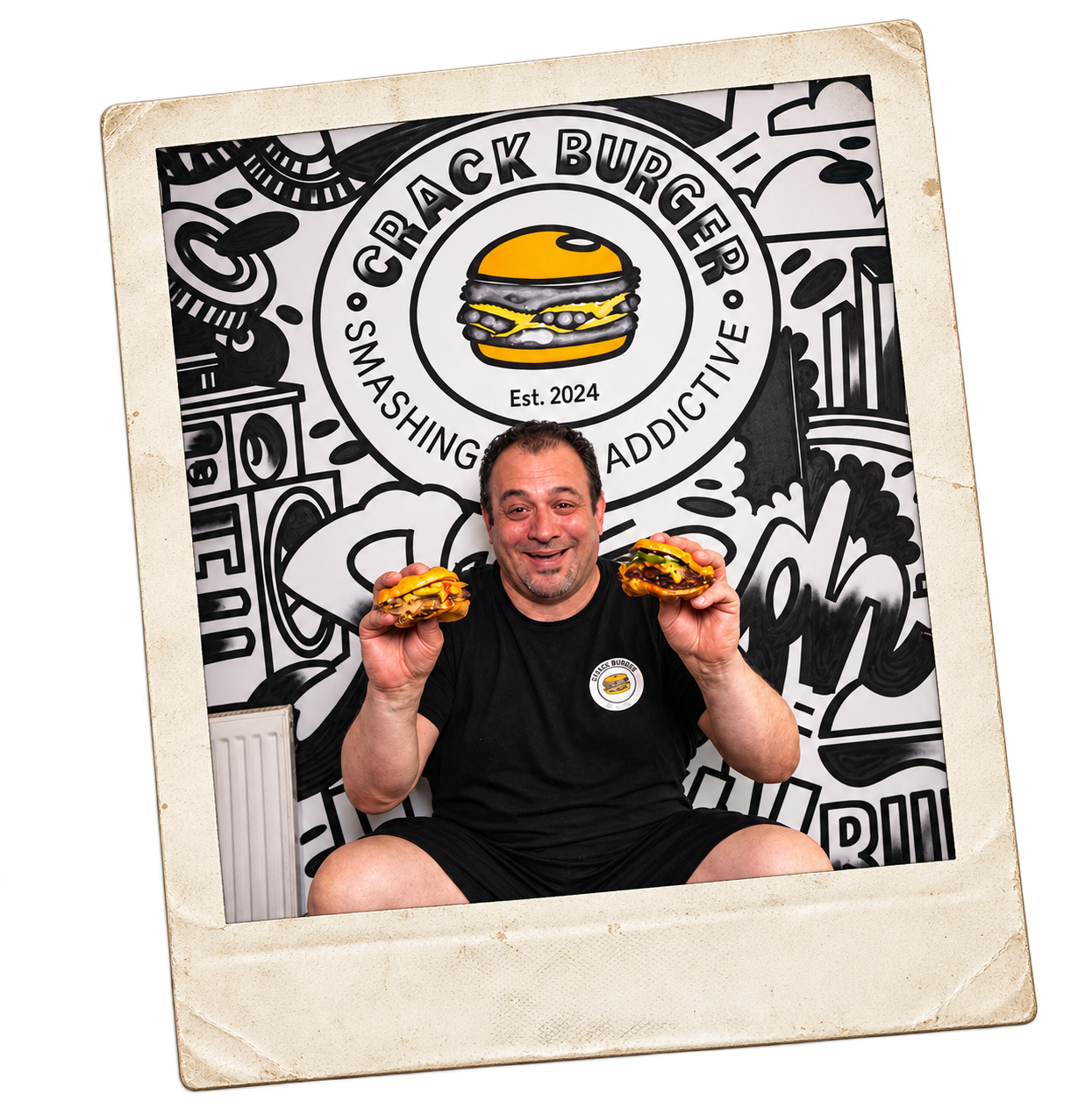 Crack Burger's owner holding up two smashburgers in front of a Crack Burger mural, shown as a tilted polaroid